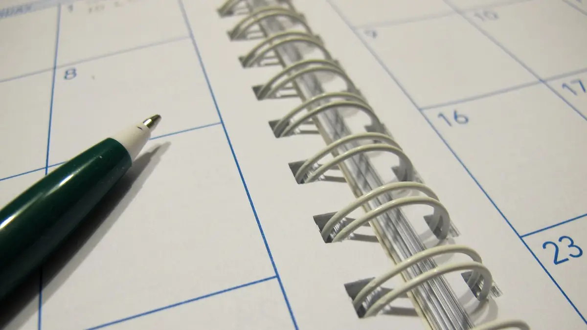 Agenda de espiral abierta con una lapicera apoyada sobre los días numerados